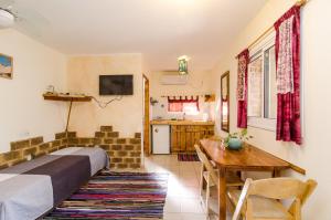 1 dormitorio con cama, mesa y cocina en Desert Routes Inn Shvilim ba Midbar en H̱aẕeva