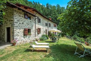 a stone house with a table and benches in the yard at Agriturismo Il Gufo in San Marcello Pistoiese