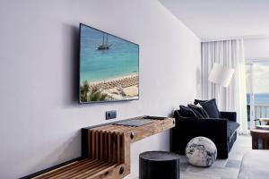 a living room with a view of the beach and a tv at Royal Myconian - Leading Hotels of the World in Elia Beach