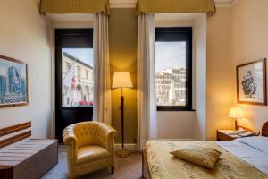 a bedroom with a bed and a chair and two windows at Hotel Roma in Florence