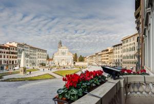 Un gruppo di fiori rossi su un cornicione in una città di Hotel Roma a Firenze
