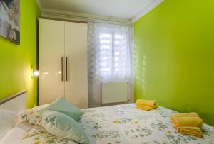 a bedroom with green walls and a bed with yellow towels at Apartments Ani in Veli Lošinj