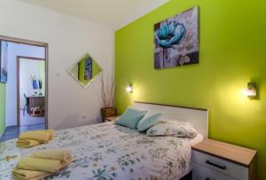 sypialnia z łóżkiem i zieloną ścianą w obiekcie Apartments Ani w mieście Veli Lošinj