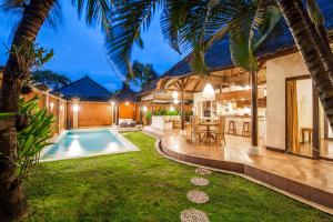 a backyard with a swimming pool and a house at Alizee Villa in Seminyak