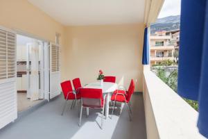 comedor con mesa blanca y sillas rojas en Apartments Bella, en Podgora