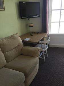 a living room with a couch and a table with a television at Gateway Lodge in Cleckheaton