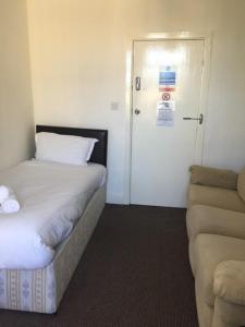 a small room with a bed and a door with a couch at Gateway Lodge in Cleckheaton