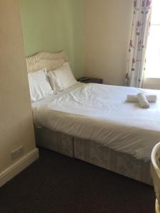 a bed with white sheets and pillows in a room at Gateway Lodge in Cleckheaton