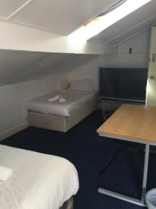 a small room with two beds and a desk at Gateway Lodge in Cleckheaton