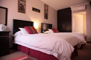 a bedroom with two beds with white sheets and red pillows at The Lazy Grape Guest Lodge & Spa in Benoni