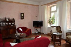 a living room with red chairs and a tv at Gutshaus Zietlitz in Dobbin