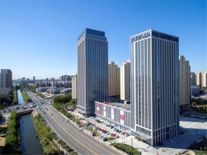 dwa wysokie budynki w mieście z rzeką w obiekcie Ariva Tianjin Zhongbei Hotel & Serviced Apartment w mieście Tiencin