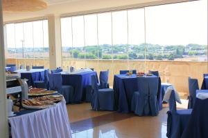 Habitación con mesas y sillas azules y ventanas grandes. en Grand Hotel Dei Cavalieri, en Maruggio