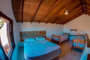 a bedroom with a blue bed and two chairs at Apoena Casas de Aluguel in Laguna