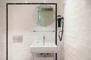 Baño blanco con lavabo y espejo en Praktik Vinoteca en Barcelona