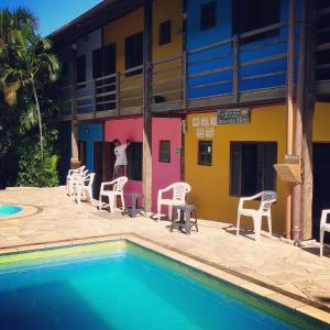 a hotel with a pool and chairs and a building at Maresias Hostel & Suites in Maresias