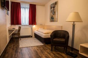 ein Hotelzimmer mit einem Bett, einem Stuhl und einem Schreibtisch in der Unterkunft Gasthof Stocker in Landsham