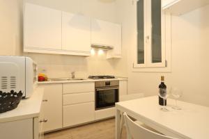 フィレンツェにあるCristina Suiteの白いキャビネットとワイングラス付きのテーブルが備わるキッチン
