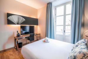a hotel room with a bed and a desk and a window at Petit Palace Santa Cruz in Seville +46 photos