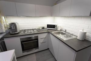 a white kitchen with a sink and a microwave at Nest Optima Toruń in Toruń