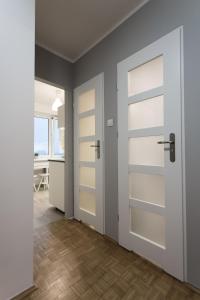 トルンにあるNest Optima Toruńの白いドアと木製の床が施された空間