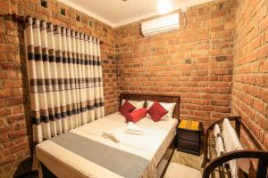 um pequeno quarto com uma cama numa parede de tijolos em Amazing Villa em Matara