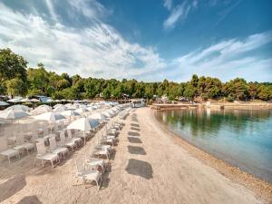 a row of chairs and umbrellas on a beach at Easyatent Mobile home Lanterna in Poreč