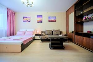 um quarto com uma cama, um sofá e uma mesa em Five Stars Pink em Chelyabinsk