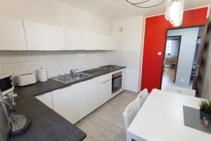 een keuken met witte kasten en een rode muur bij Nest Arena Toruń in Toruń +7 foto's