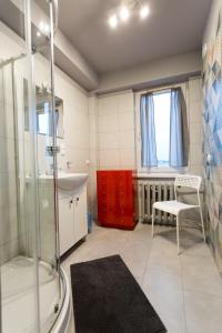 een badkamer met een douche, een wastafel en een stoel bij Nest Arena Toruń in Toruń