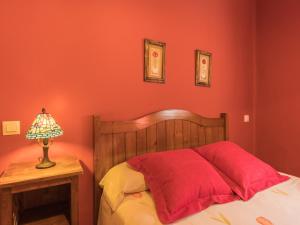 アレーナス・デ・サン・ペドロにあるLos Prejonesの赤い壁のベッド、テーブルの上のランプ