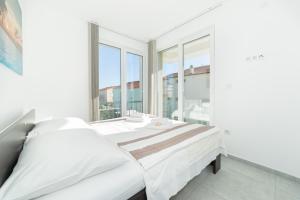 a white bedroom with two beds and a large window at Apartments M&L in Vodice +68 photos
