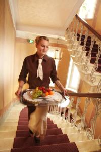 a woman walking down a staircase carrying a tray of fruit at Hotel Astor in Vaasa