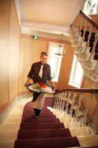 mężczyzna schodzący po schodach niosący tacę z jedzeniem w obiekcie Hotel Astor w mieście Vaasa