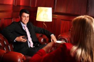 un hombre con traje y corbata sentado en un sofá con una mujer en Hotel Astor en Vaasa