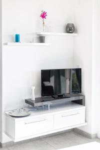 un centro de entretenimiento blanco con TV en la pared en Apartments M&L en Vodice