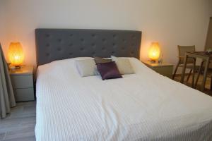 a bedroom with a large white bed with two lamps at Luxury Studio 42 De Silva in Mamaia