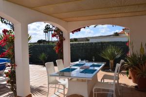 a patio with a glass table and white chairs at Villa Rochelle in Caleta De Fuste