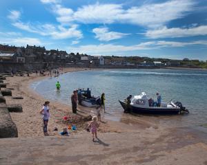 un grupo de personas en una playa con barcos en Albero Apartment en Eyemouth