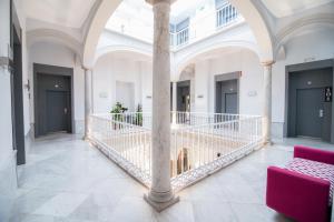 Habitación grande con un pilar y una silla morada. en Petit Palace Santa Cruz en Sevilla