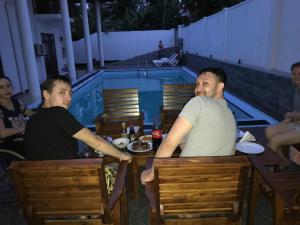 two men sitting at a table in front of a swimming pool at Villa 234 in Galle