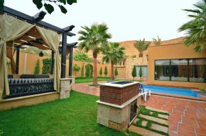 a backyard with a barbecue grill and a house at Marbella Resort in Al ‘Ammārīyah