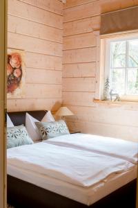 a bed in a wooden room with a window at Jagdhaus zur Bischofsmühle in Helmbrechts