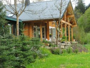 uma cabana de madeira com um alpendre e um quintal em Jagdhaus zur Bischofsmühle em Helmbrechts
