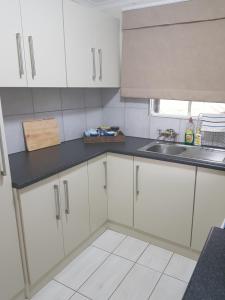 a kitchen with white cabinets and a sink at Piccadilly Farm Cottages in Lions River