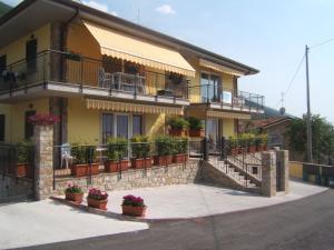 una casa gialla con balconi e piante in vaso di Mary Apartments a Brenzone sul Garda