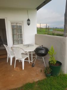 a white table and chairs and a grill on a patio at Piccadilly Farm Cottages in Lions River