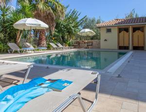 a swimming pool with a table and chairs next to it at Azalea in Vasiliki