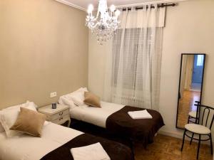 a bedroom with two beds and a chandelier at Apartamento Vitoria II in Vitoria-Gasteiz