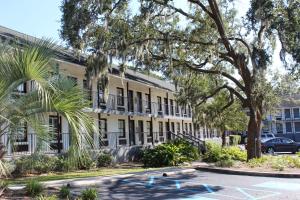 ein großes weißes Gebäude mit Bäumen und einem Parkplatz in der Unterkunft Charleston Creekside Inn in Charleston
